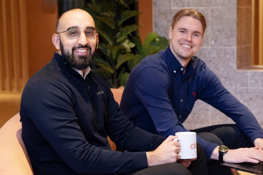 To kolleger der sidder og smiler i et mødelokale hos Cloudworks